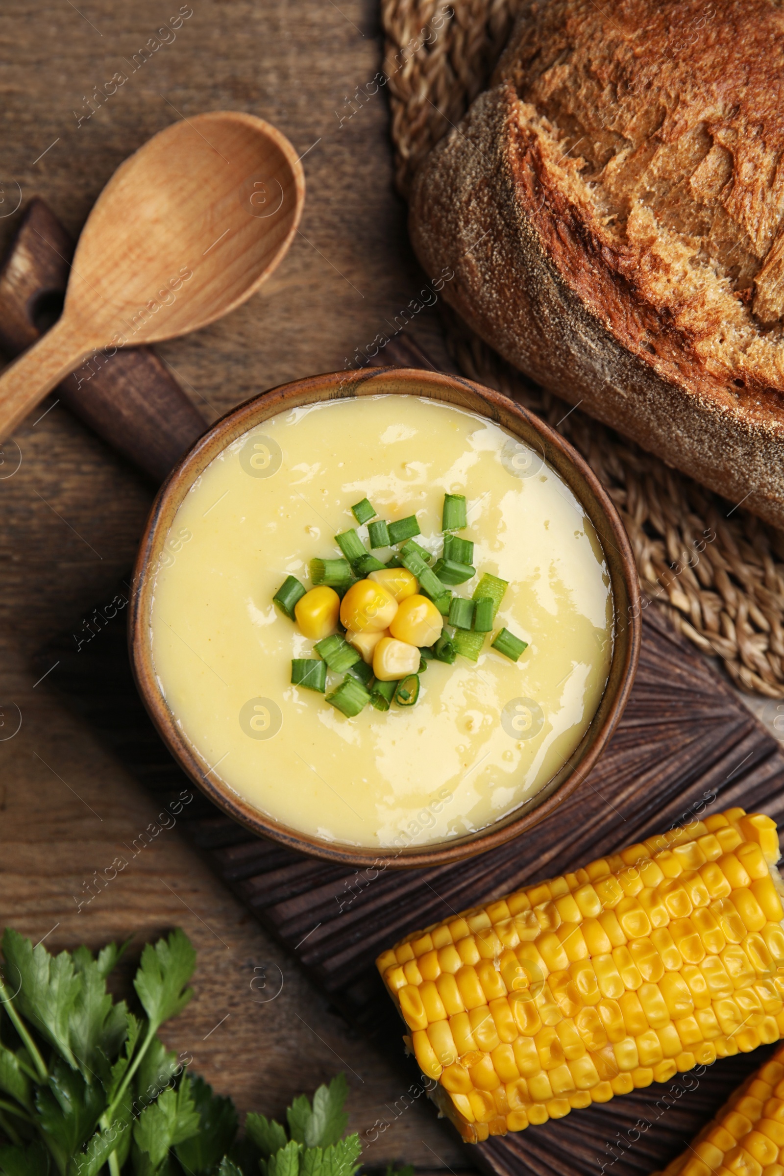 Photo of Delicious corn cream soup served on wooden table, flat lay