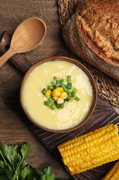 Delicious corn cream soup served on wooden table, flat lay