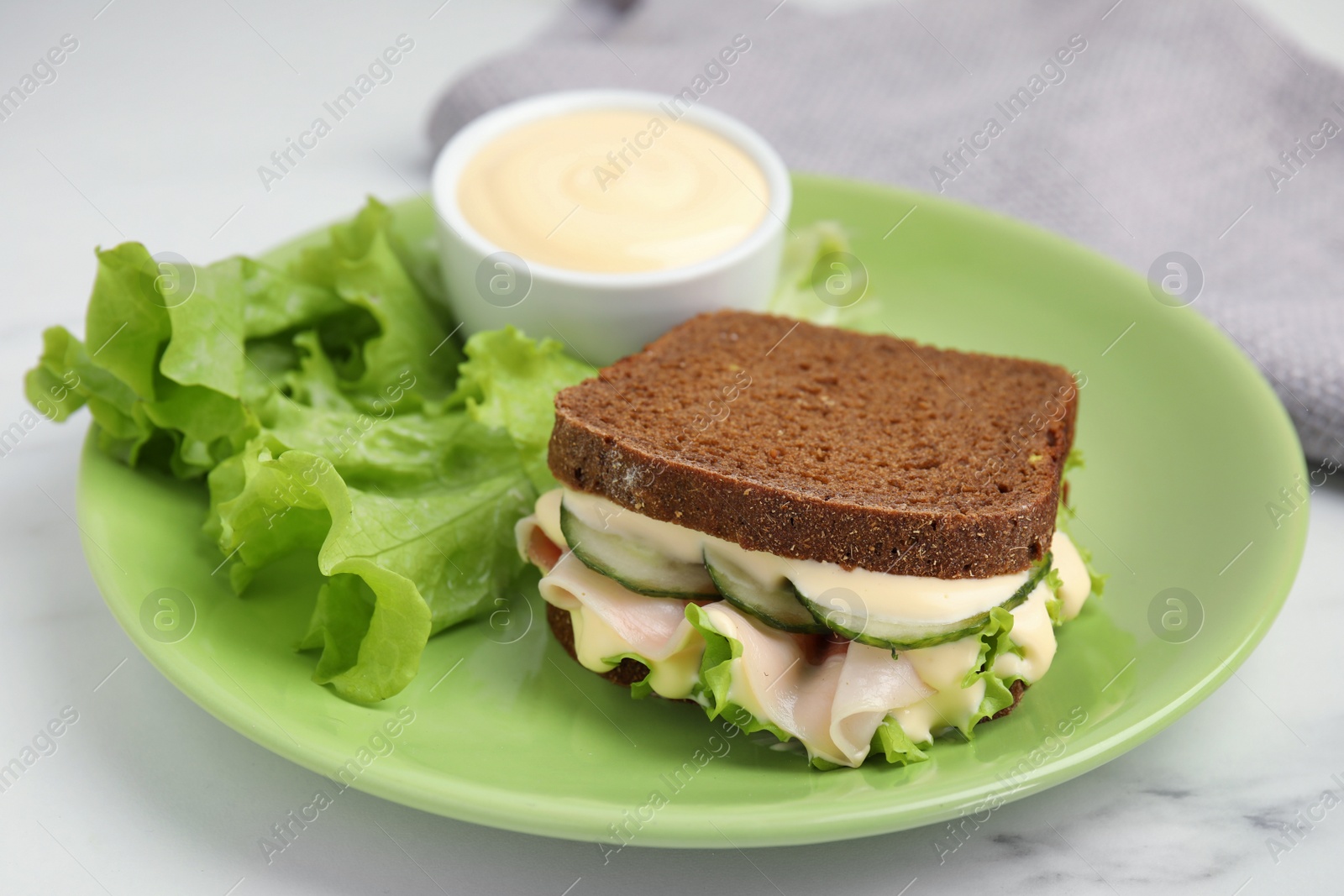 Photo of Delicious sandwich with vegetables, ham and mayonnaise on white table, closeup