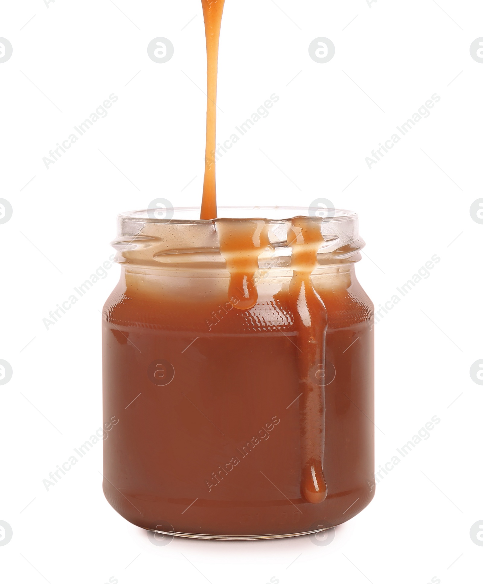 Photo of Tasty caramel sauce pouring into jar isolated on white