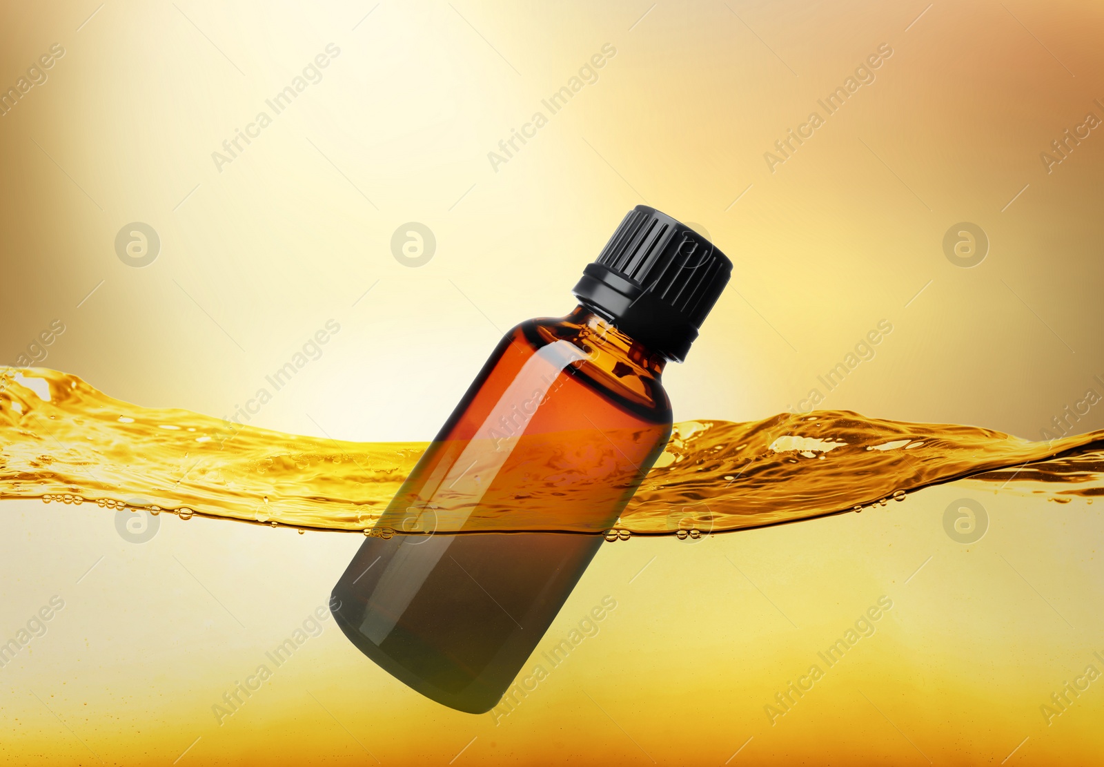 Image of Bottle of cosmetic product floating in essential oil against gold gradient background