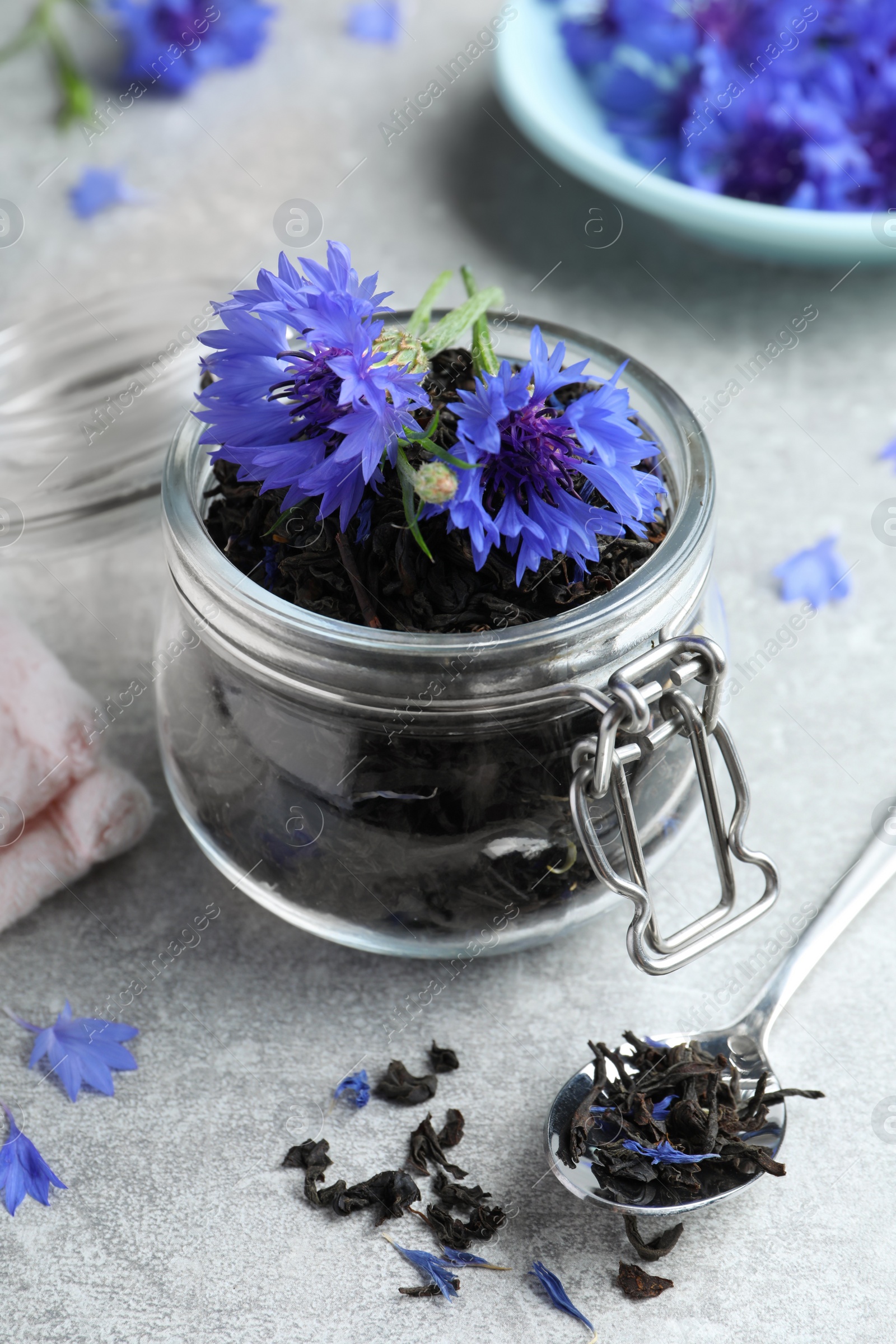 Photo of Dry tea leaves and cornflowers on light table