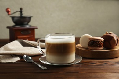 Photo of Aromatic coffee in cup, spoon and macarons on wooden table