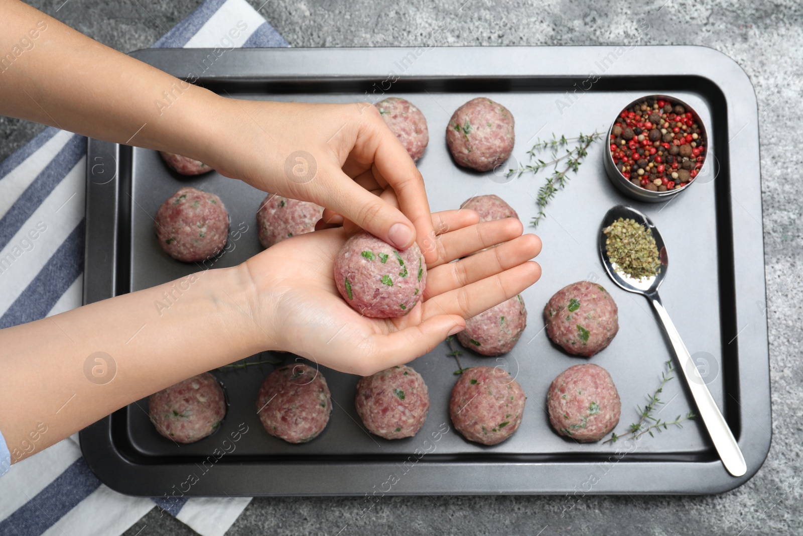Photo of Woman making fresh raw meatballs at grey table, top view