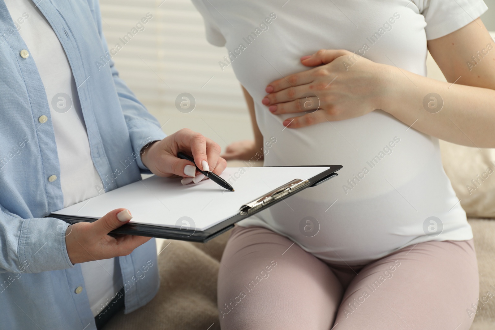 Photo of Doula working with pregnant woman indoors, closeup. Preparation for child birth