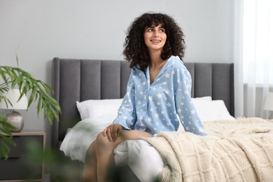 Beautiful young woman in stylish pyjama on bed at home