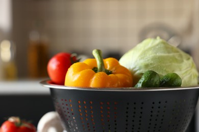 Photo of Metal colander with different wet vegetables on table, closeup