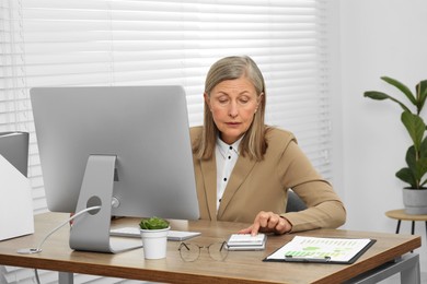 Senior accountant working at wooden desk in office