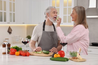 Photo of Affectionate senior couple cooking together in kitchen