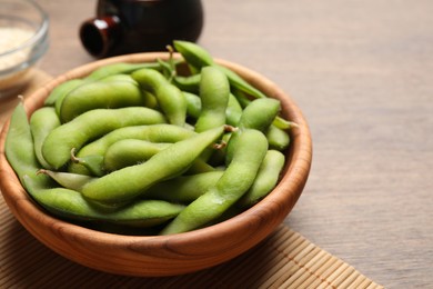 Photo of Green edamame beans in pods served on wooden table. Space for text