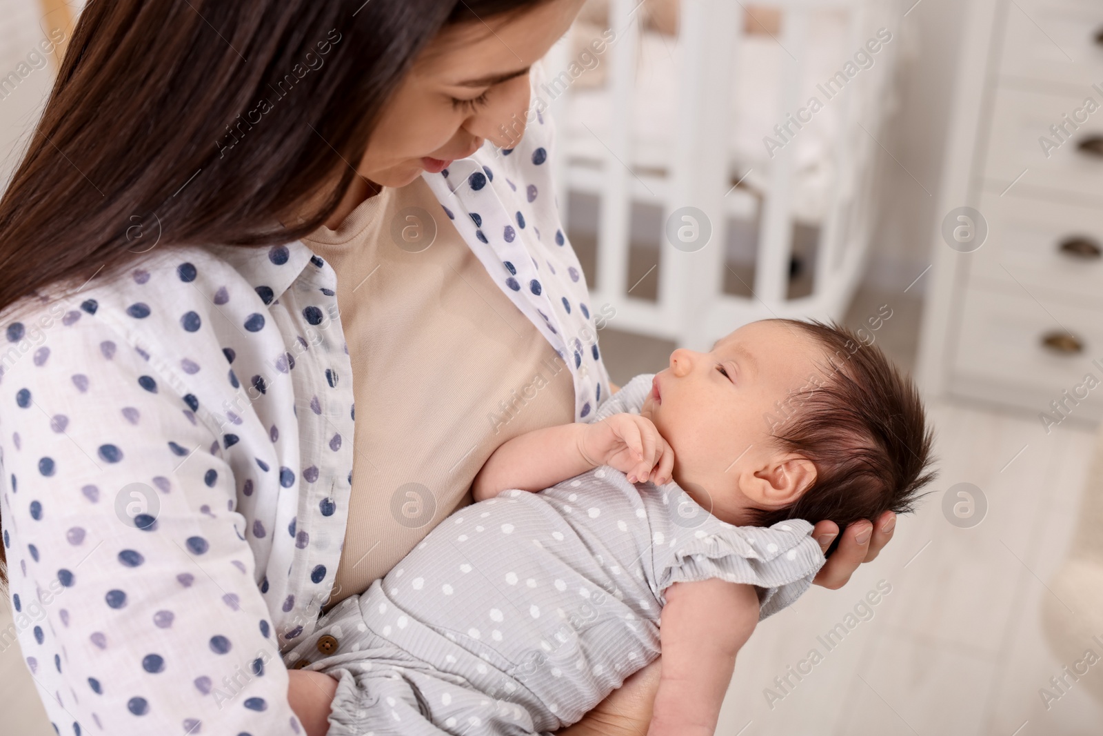 Photo of Mother with her sleeping newborn baby at home