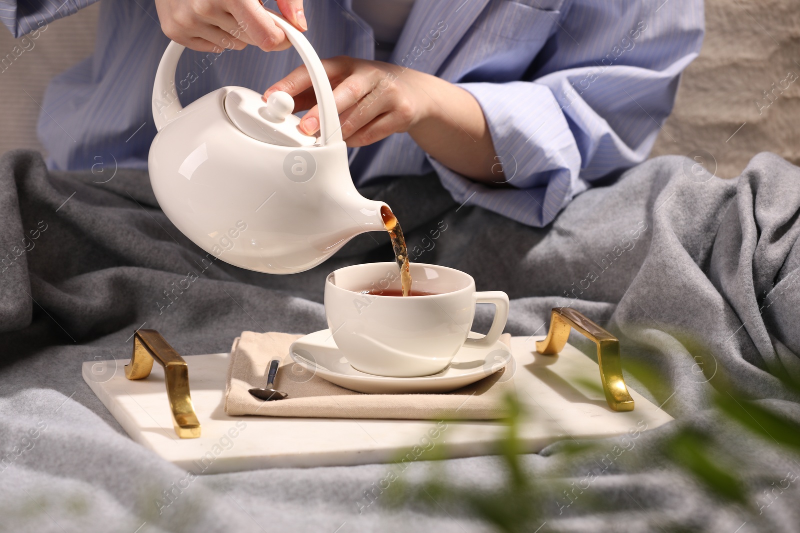 Photo of Woman pouring aromatic tea into cup at table, closeup