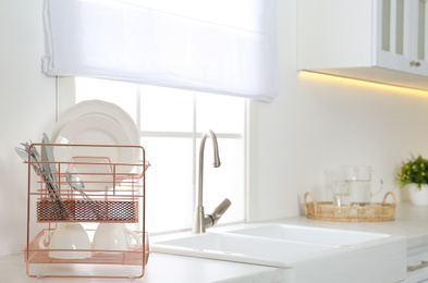 Photo of Clean dishes on drying rack in modern kitchen interior