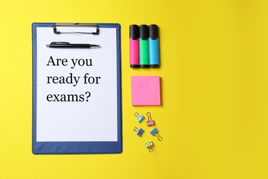 Photo of Clipboard with phrase Are You Ready For Exams and stationery on yellow background, flat lay. Space for text