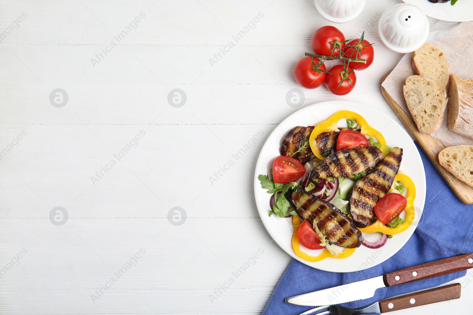 Photo of Delicious salad with roasted eggplant served on white wooden table, flat lay. Space for text