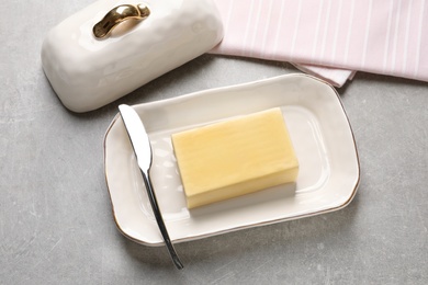 Dish with fresh butter and knife on table, view from above