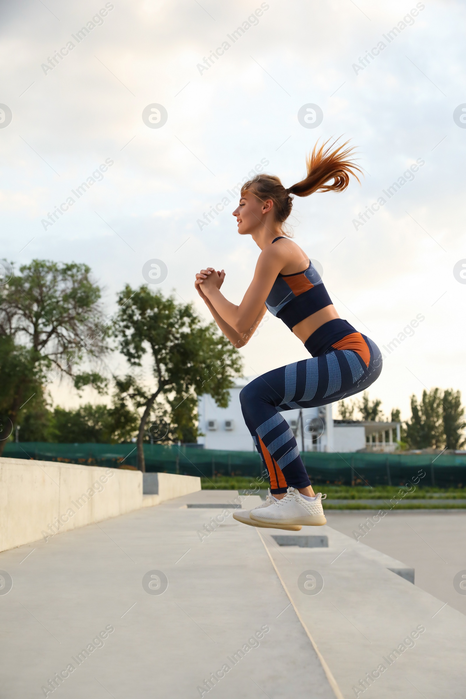 Photo of Beautiful woman in sportswear jumping on steps outdoors