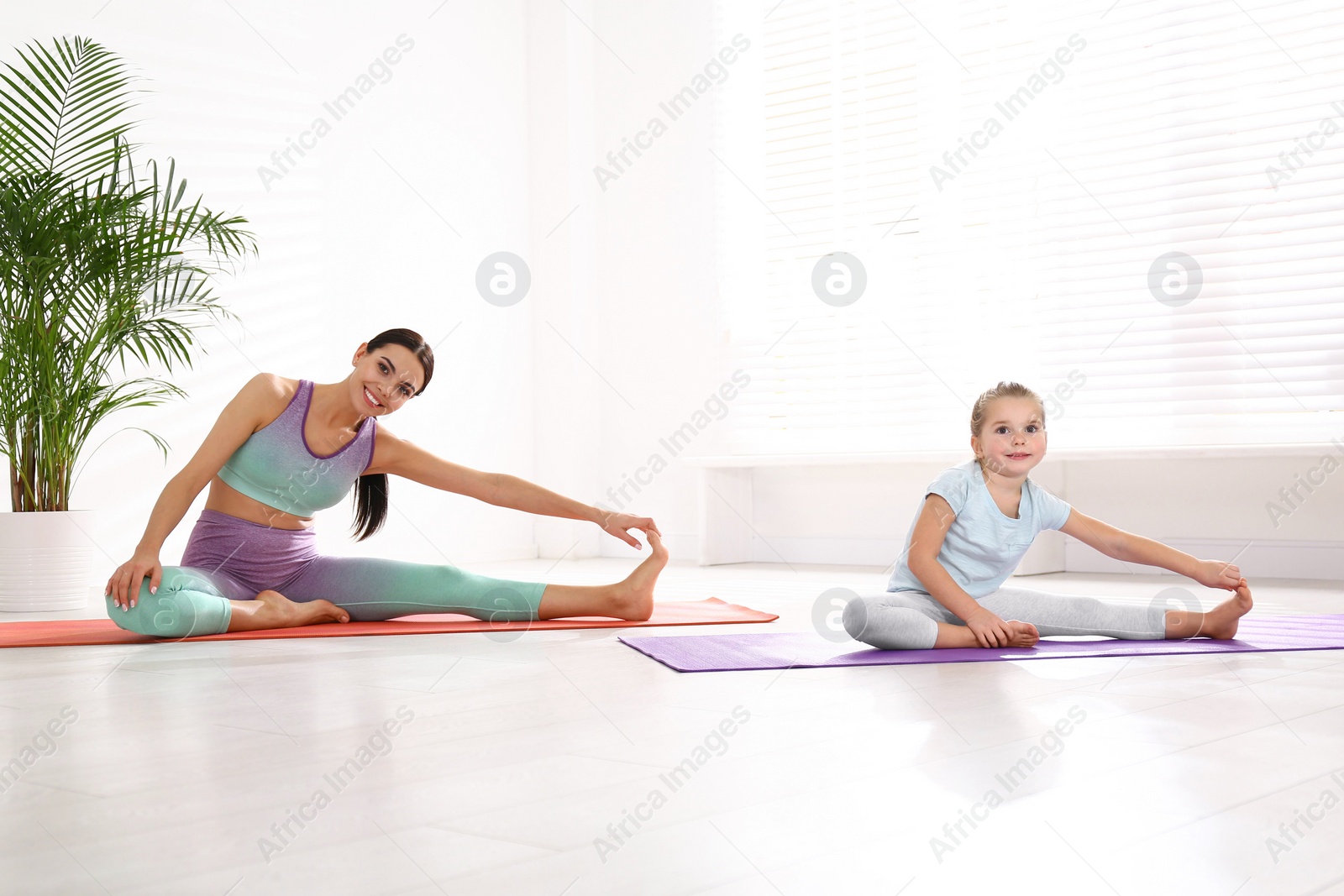 Photo of Woman and daughter doing yoga together at home. Fitness lifestyle