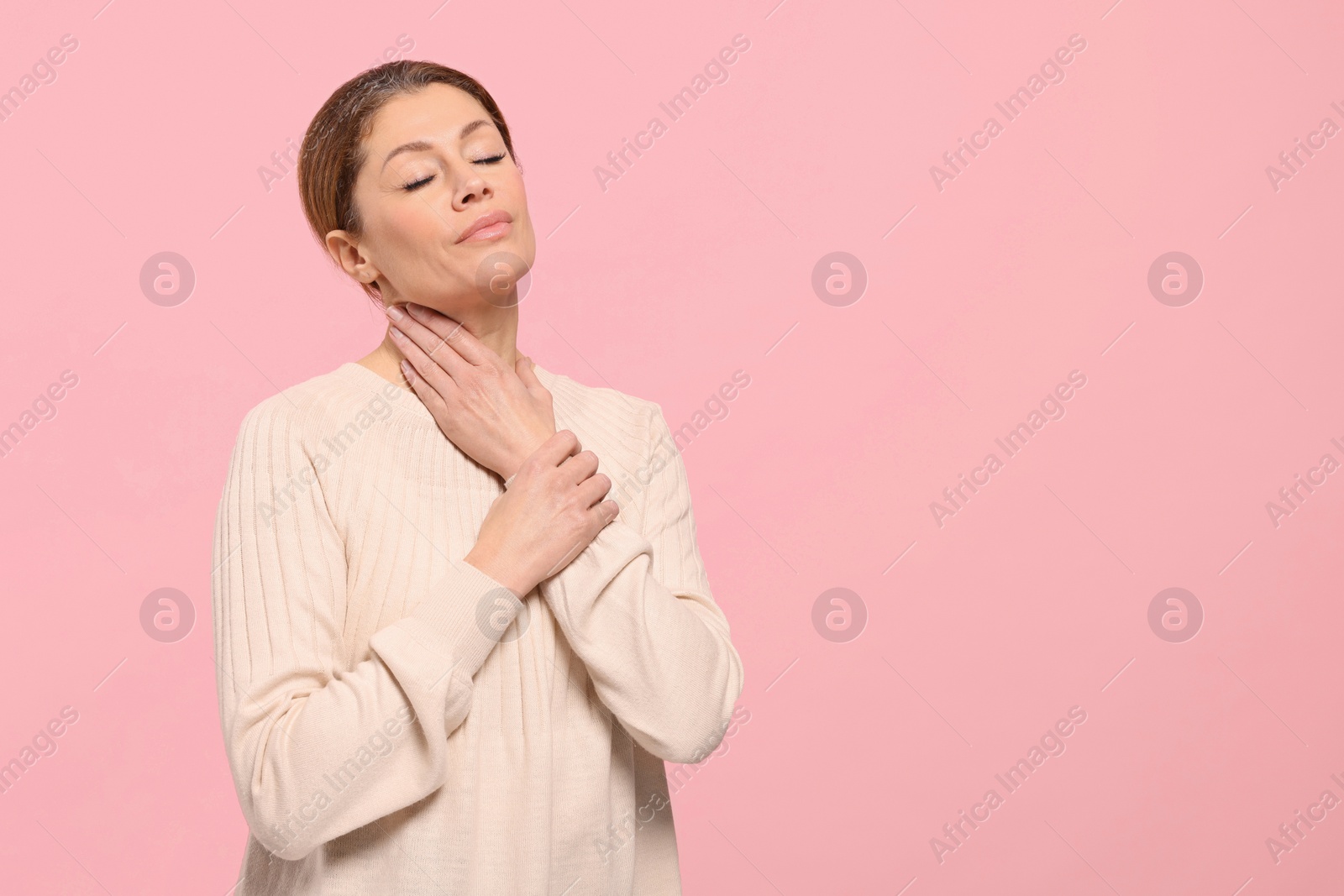 Photo of Woman suffering from sore throat on pink background. Space for text