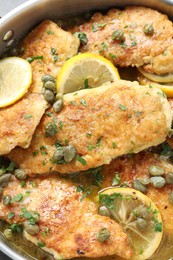 Photo of Delicious chicken piccata with herbs and lemons as background, closeup