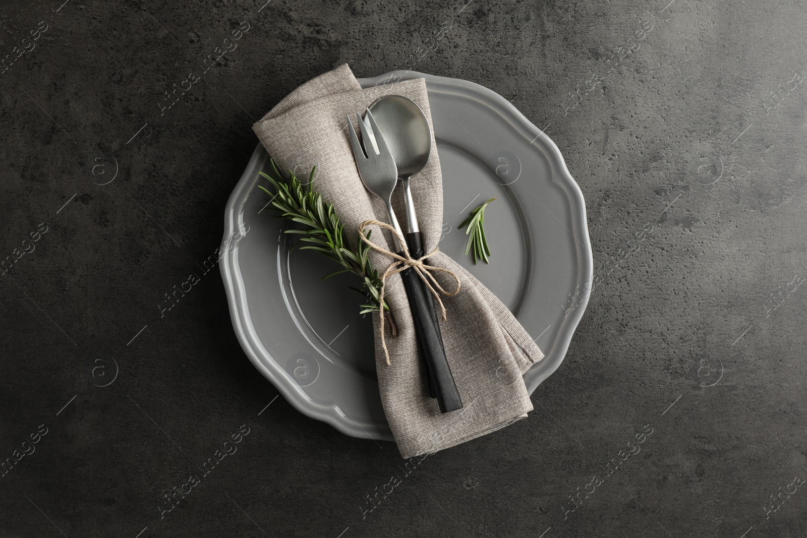 Photo of Stylish setting with cutlery and napkin on black table, top view