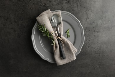 Stylish setting with cutlery and napkin on black table, top view