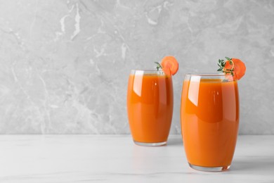Photo of Glasses with healthy carrot juice on white table. Space for text