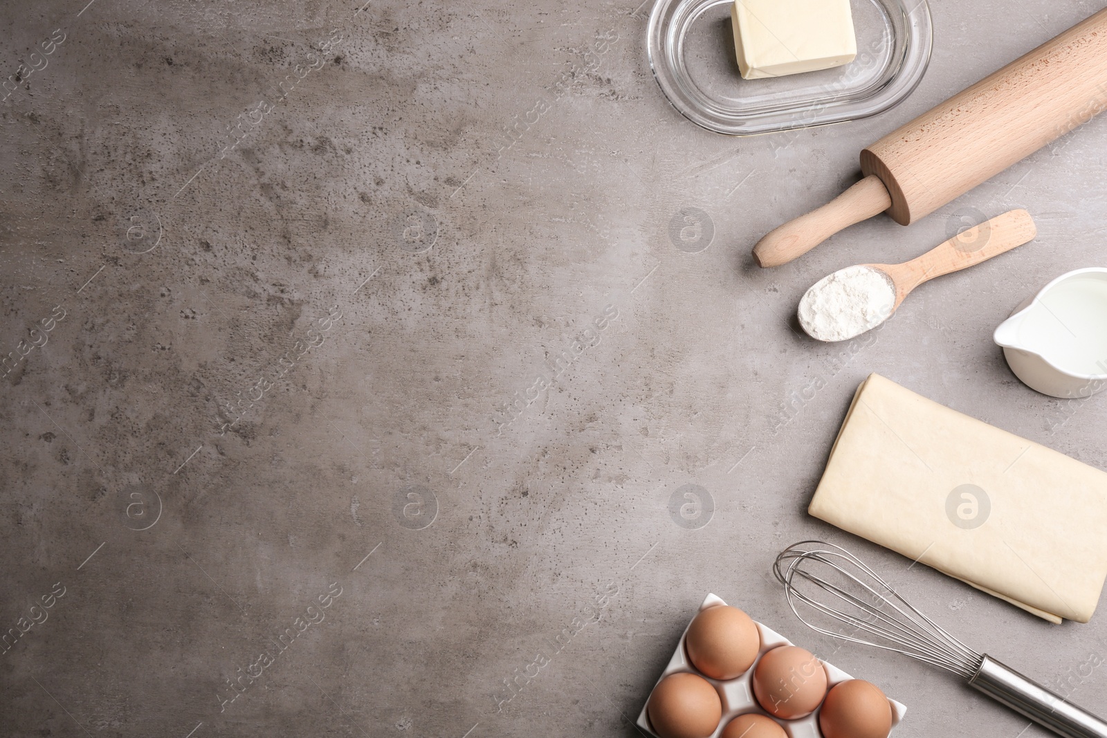 Photo of Flat lay composition with fresh dough on grey table, space for text. Puff pastry