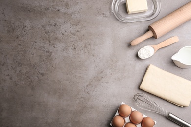 Flat lay composition with fresh dough on grey table, space for text. Puff pastry