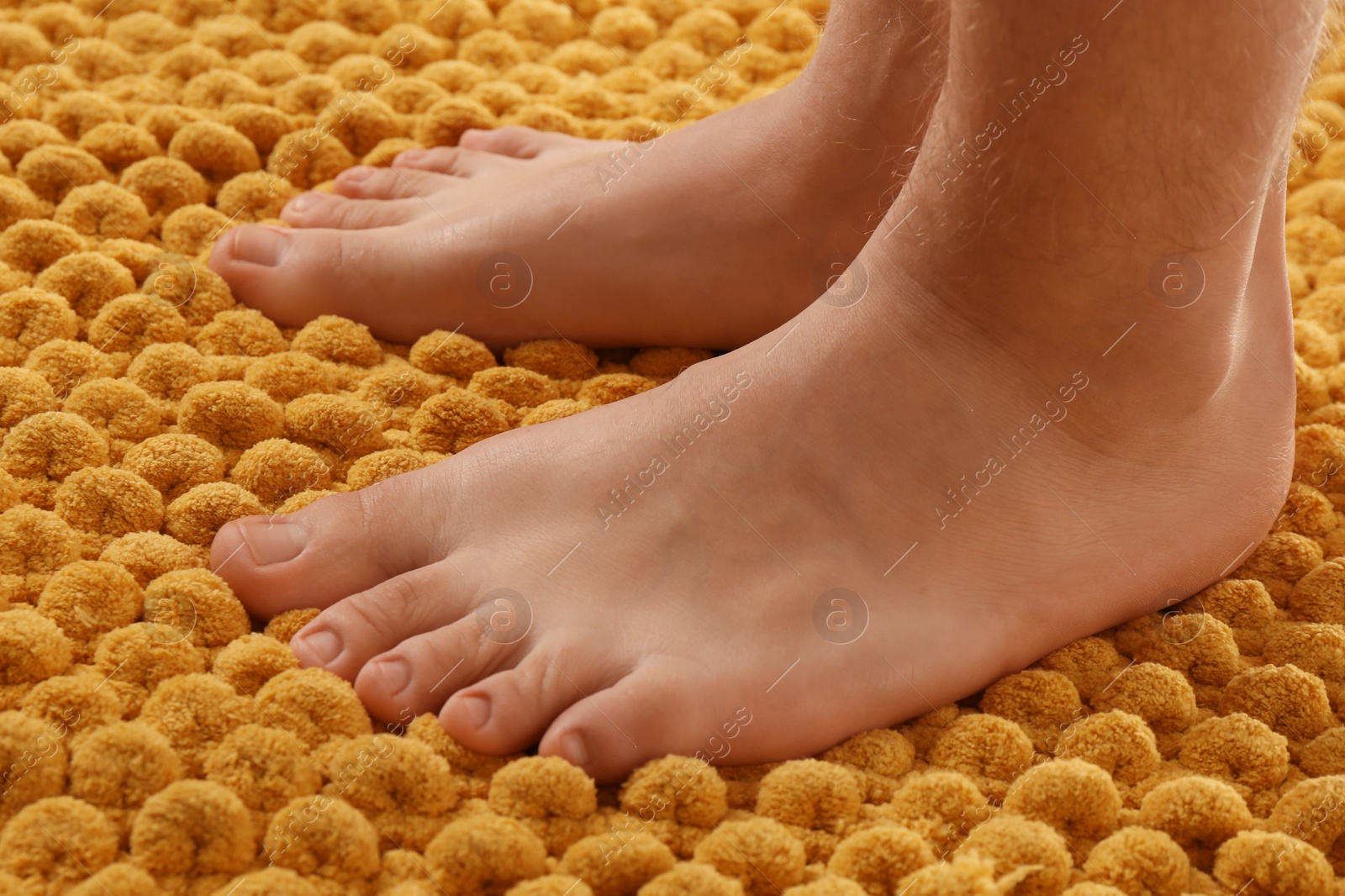 Photo of Man standing on soft orange bath mat, closeup