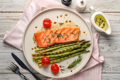 Photo of Tasty grilled salmon with tomatoes, asparagus and spices served on wooden table, flat lay