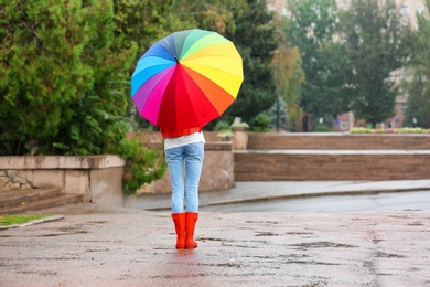Photo of Young woman with bright umbrella under rain outdoors