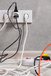 Photo of Extension cord with power plugs in sockets indoors