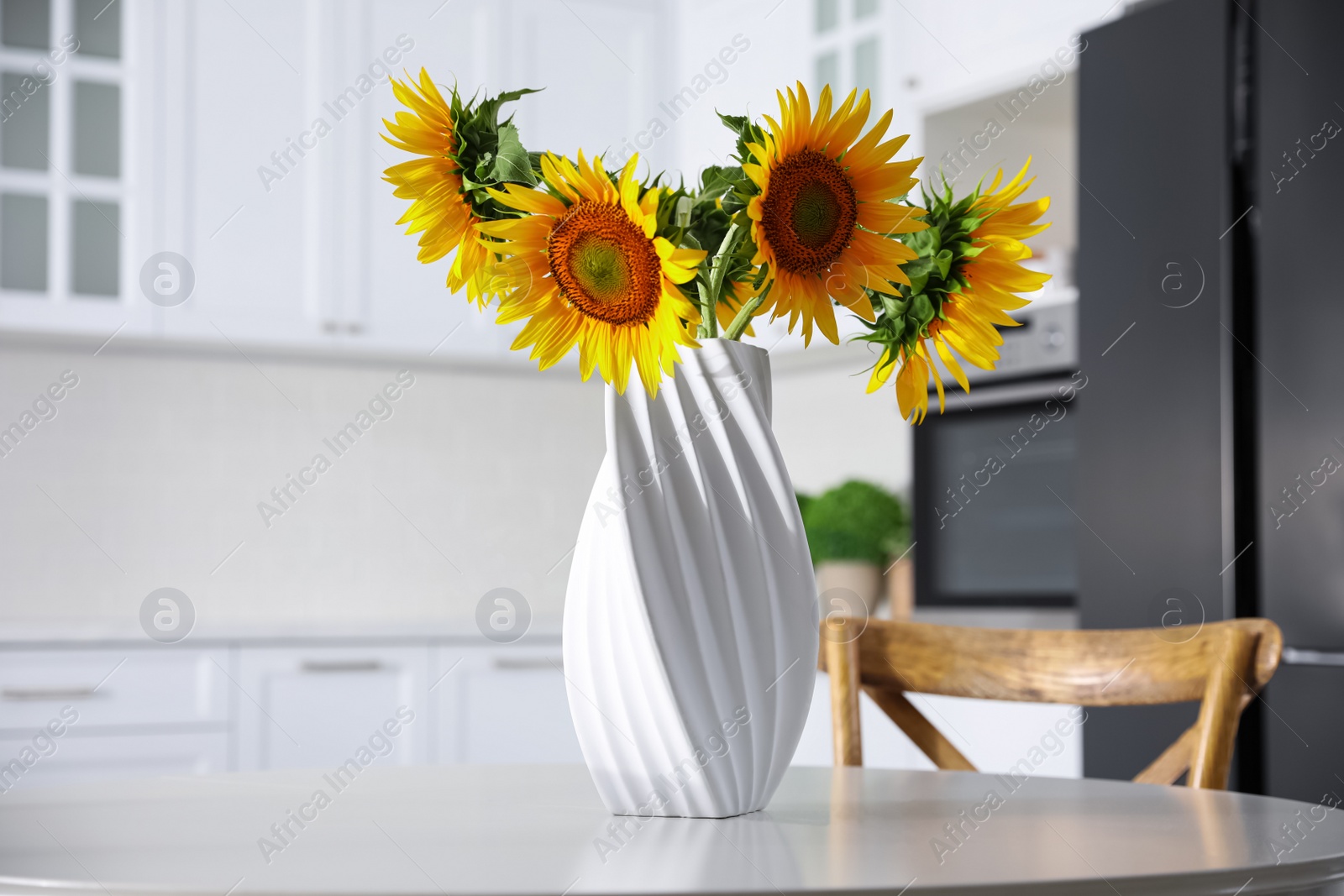 Photo of Bouquet of beautiful sunflowers on table in kitchen