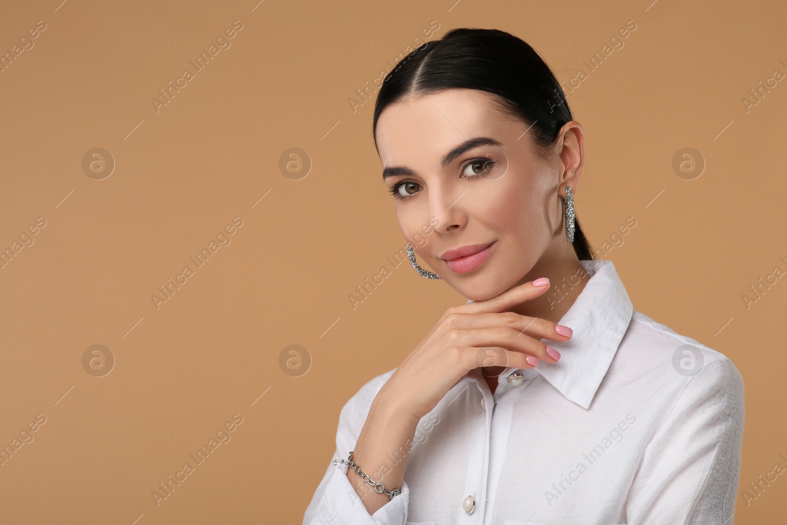 Photo of Beautiful young woman with elegant jewelry on beige background. Space for text