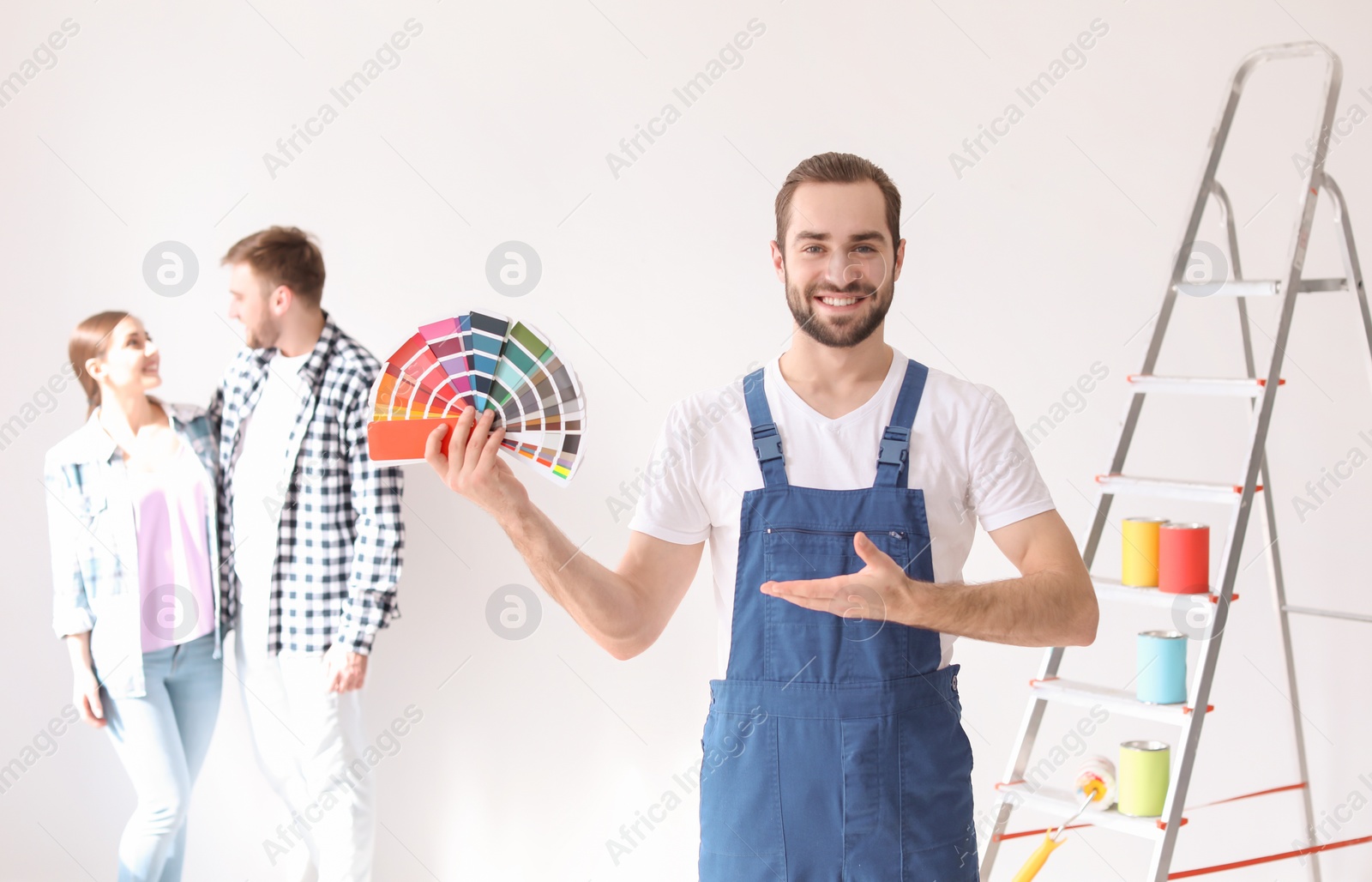 Photo of Male decorator with color palette and blurred couple on white background