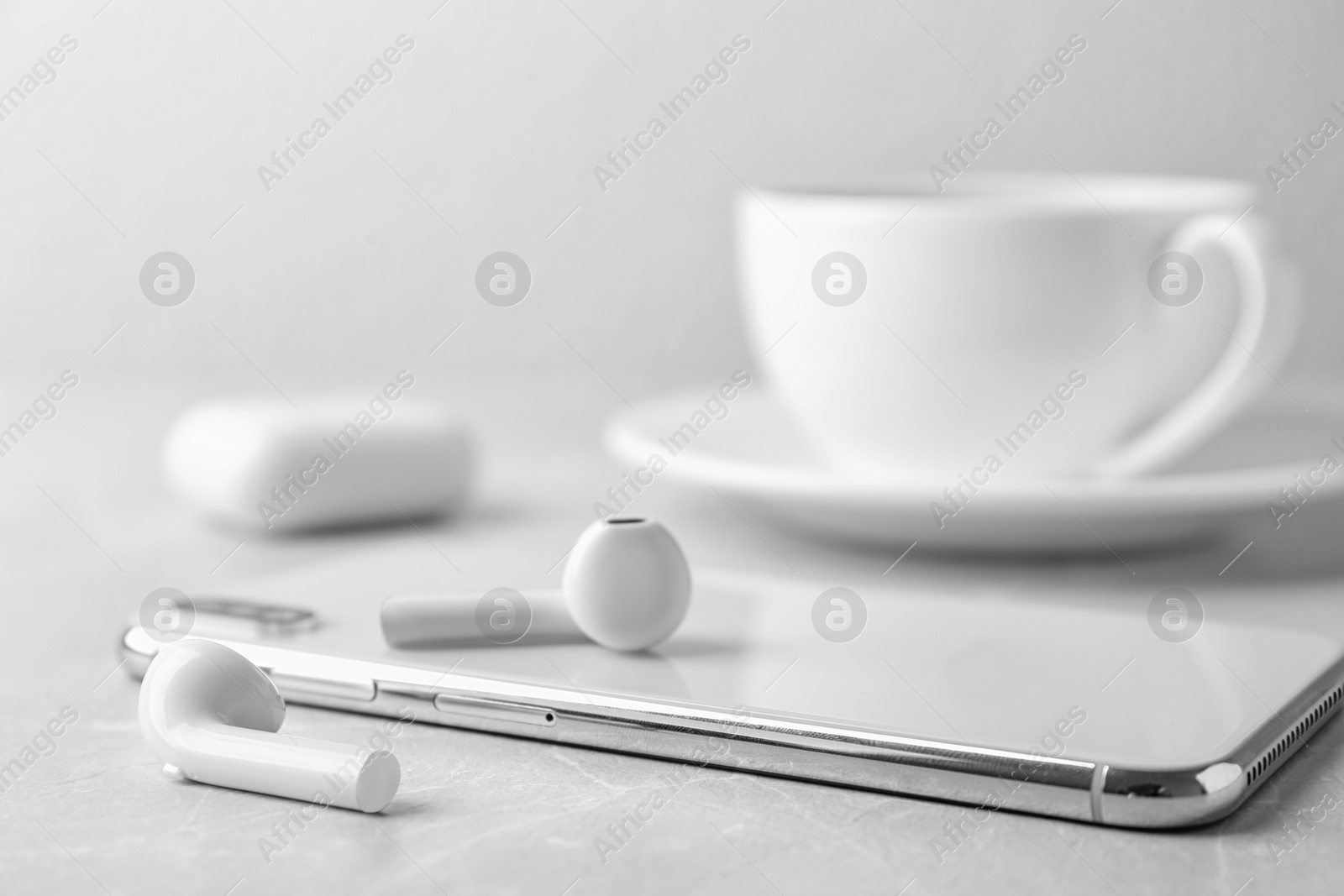 Photo of Modern wireless earphones and mobile phone on light table