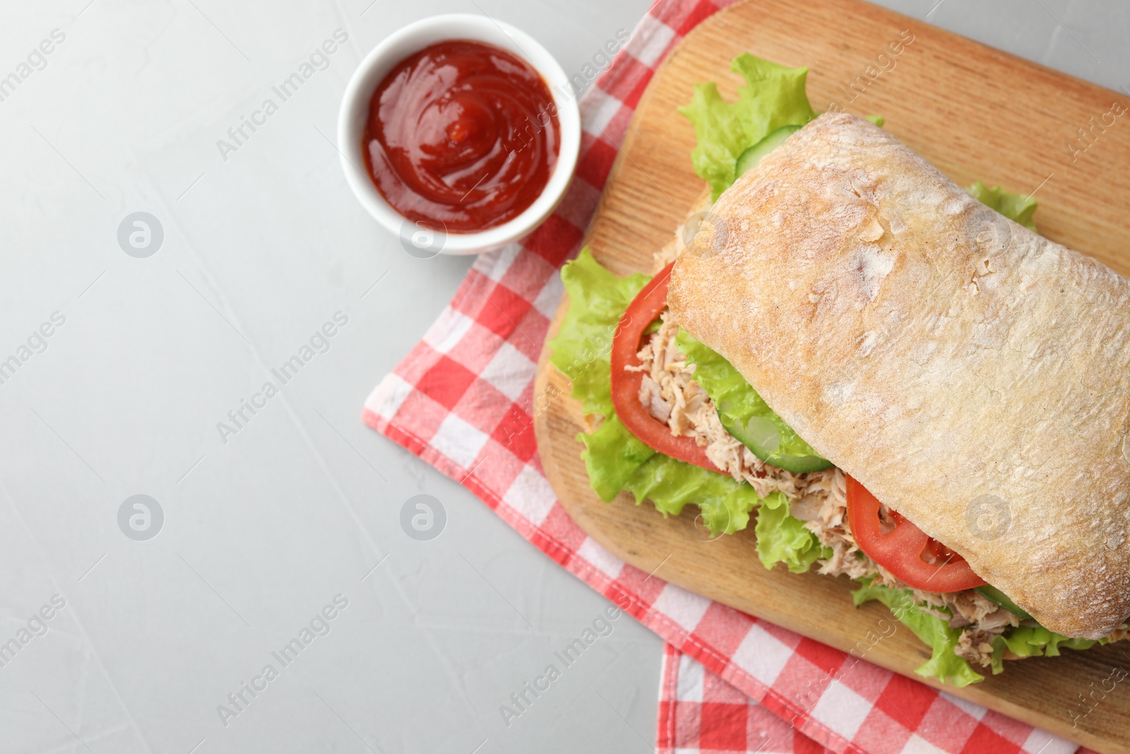 Photo of Delicious sandwich with tuna, vegetables and tomato sauce on light grey table, flat lay. Space for text