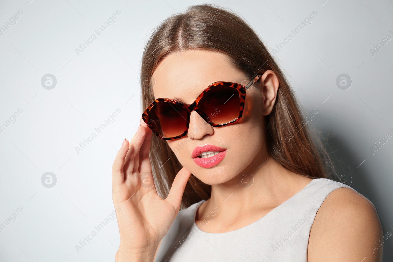 Photo of Young woman wearing stylish sunglasses on light grey background