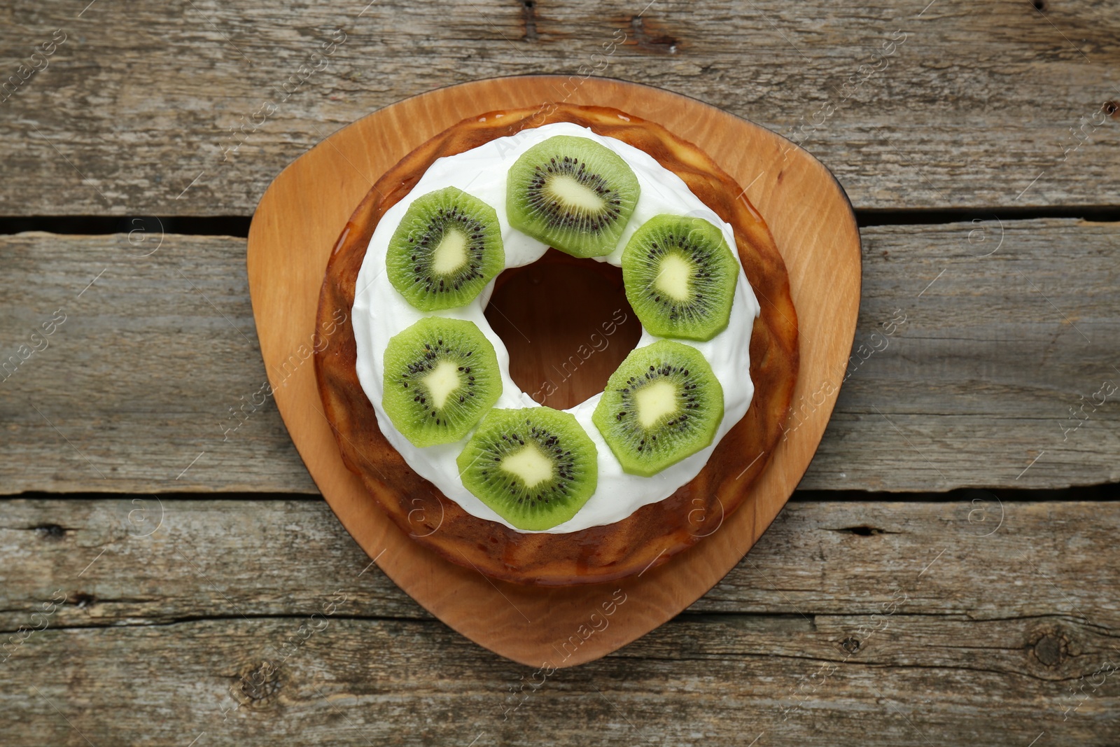 Photo of Homemade yogurt cake with kiwi and cream on wooden table, top view