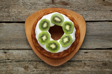 Homemade yogurt cake with kiwi and cream on wooden table, top view