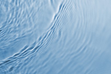 Rippled surface of clear water on light blue background, top view