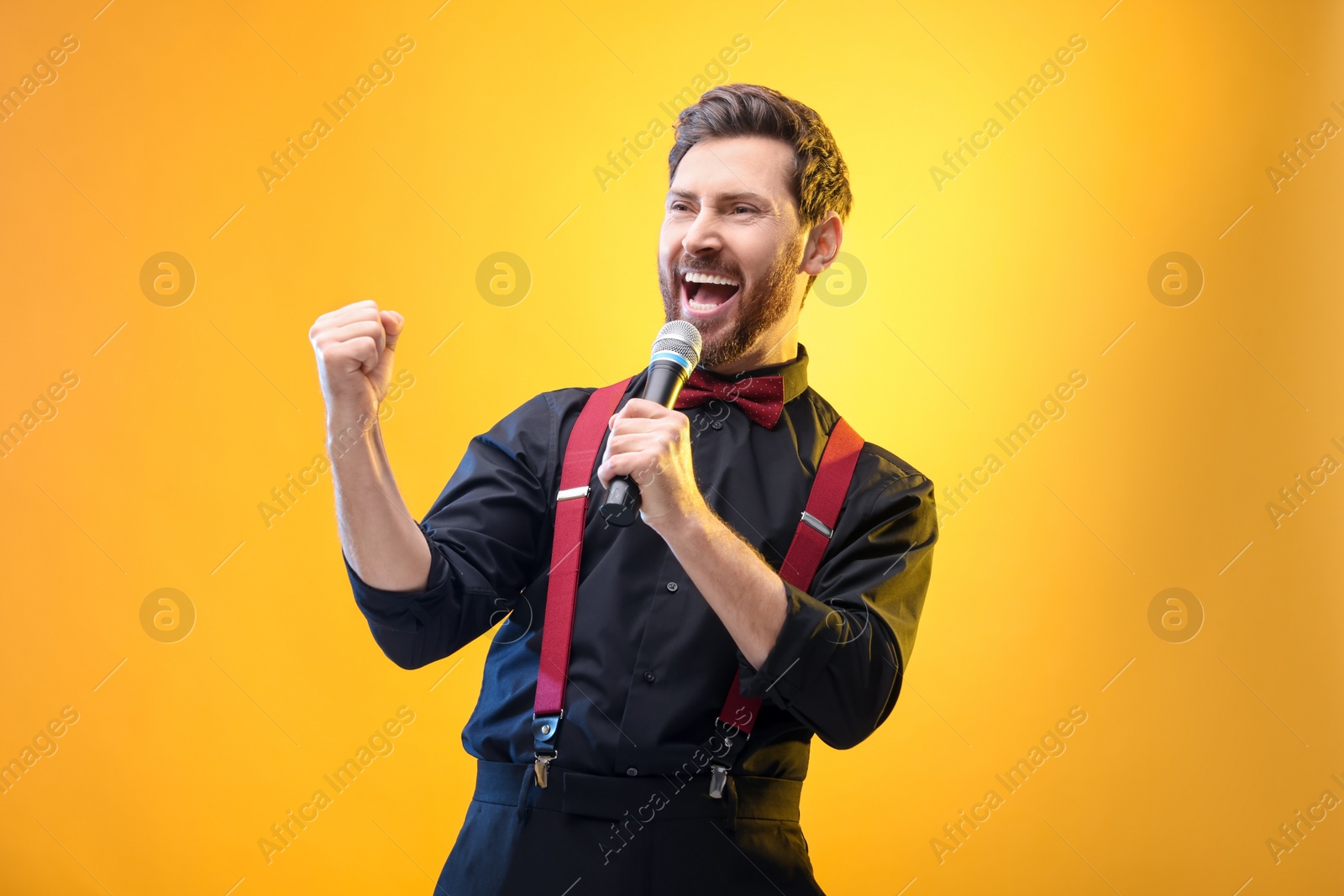 Photo of Emotional man with microphone singing on yellow background