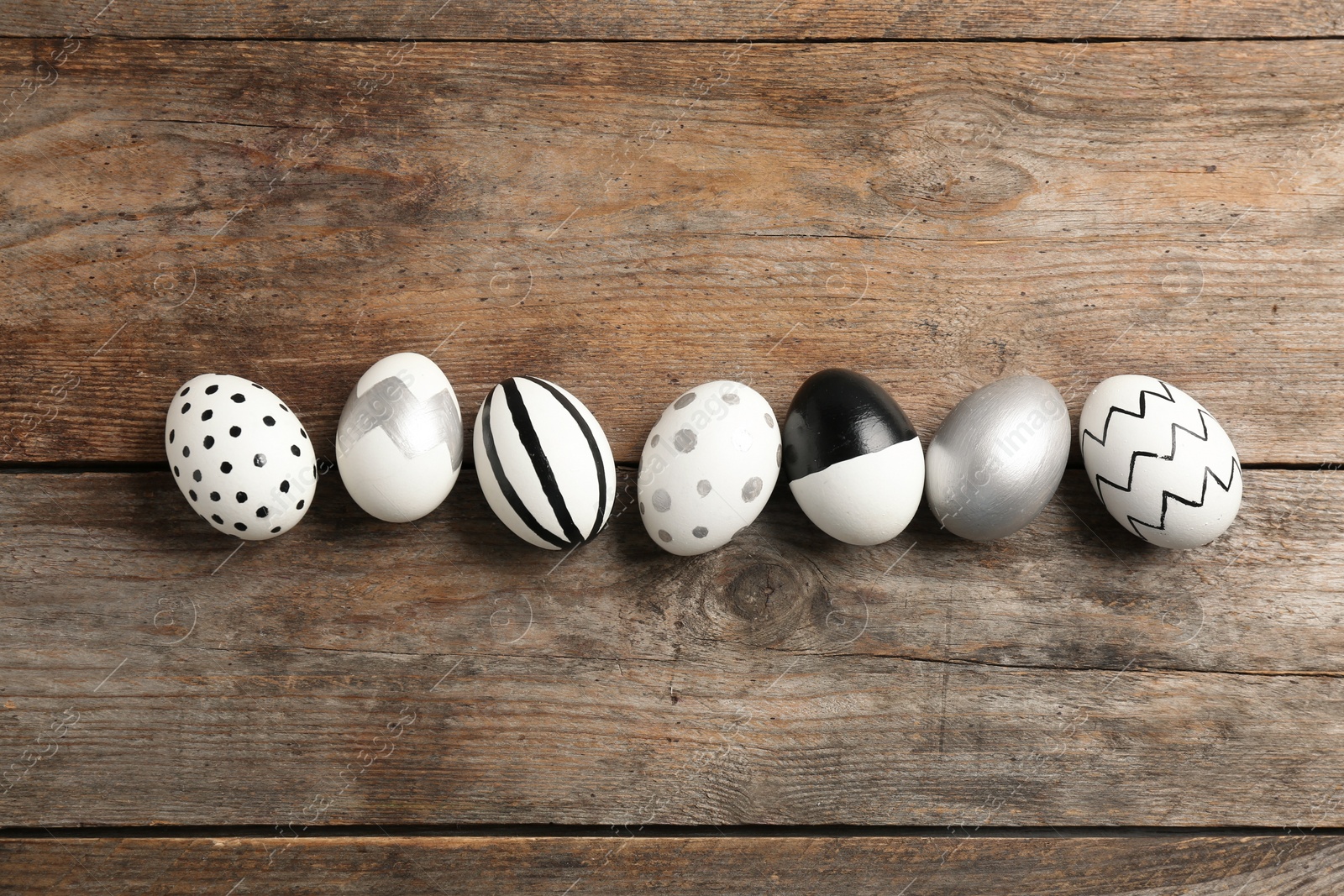 Photo of Painted Easter eggs on wooden background, flat lay