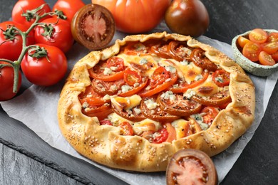 Tasty galette with tomato and cheese (Caprese galette) on dark table, closeup