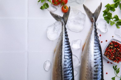 Photo of Raw mackerel, peppercorns and parsley on white tiled table, flat lay. Space for text