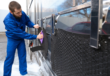 Photo of Worker wiping automobile floor mat at car wash