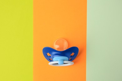 Photo of Baby pacifier on color background, top view