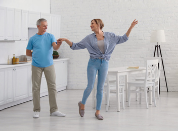 Happy senior couple dancing together in kitchen