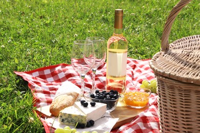 Picnic blanket with delicious food and wine outdoors on summer day